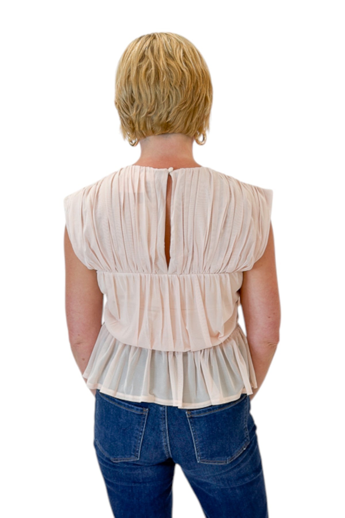 Back view of woman wearing Swagger Boutique’s Champagne Shirred Peplum Top with jeans against white studio background.