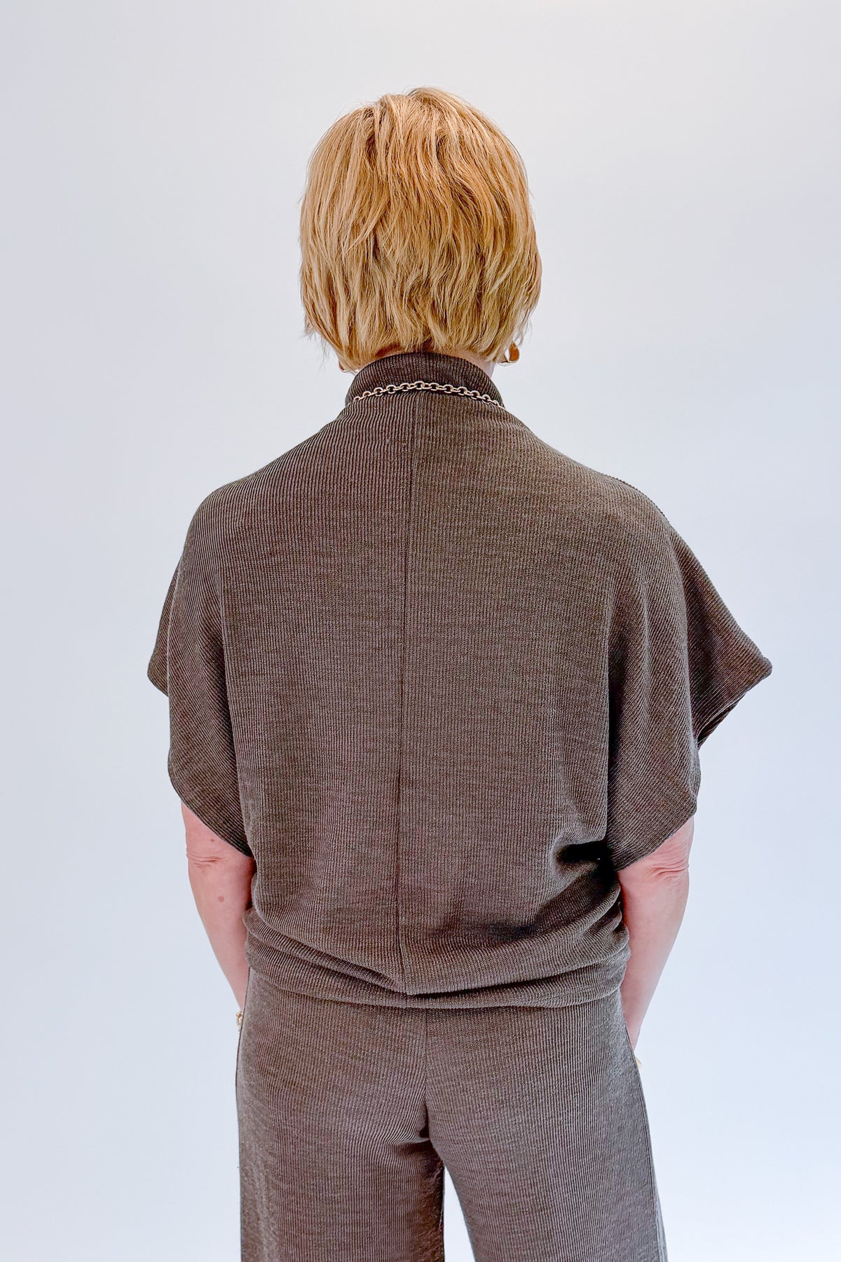 Back view of woman wearing Swagger Boutique’s Charcoal Ribbed Short Sleeve Turtleneck Top &amp; Lounge Pants against white studio background.