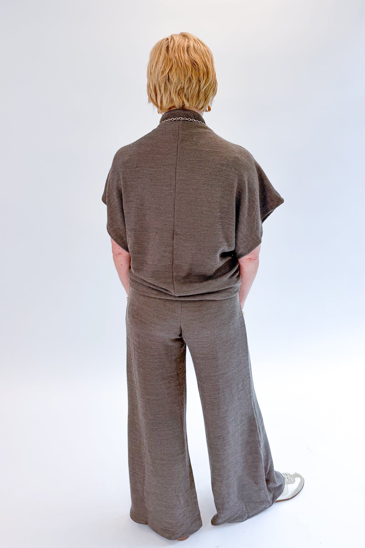Back view of woman wearing Swagger Boutique’s Charcoal Ribbed Short Sleeve Turtleneck Top &amp; Lounge Pants against white studio background.