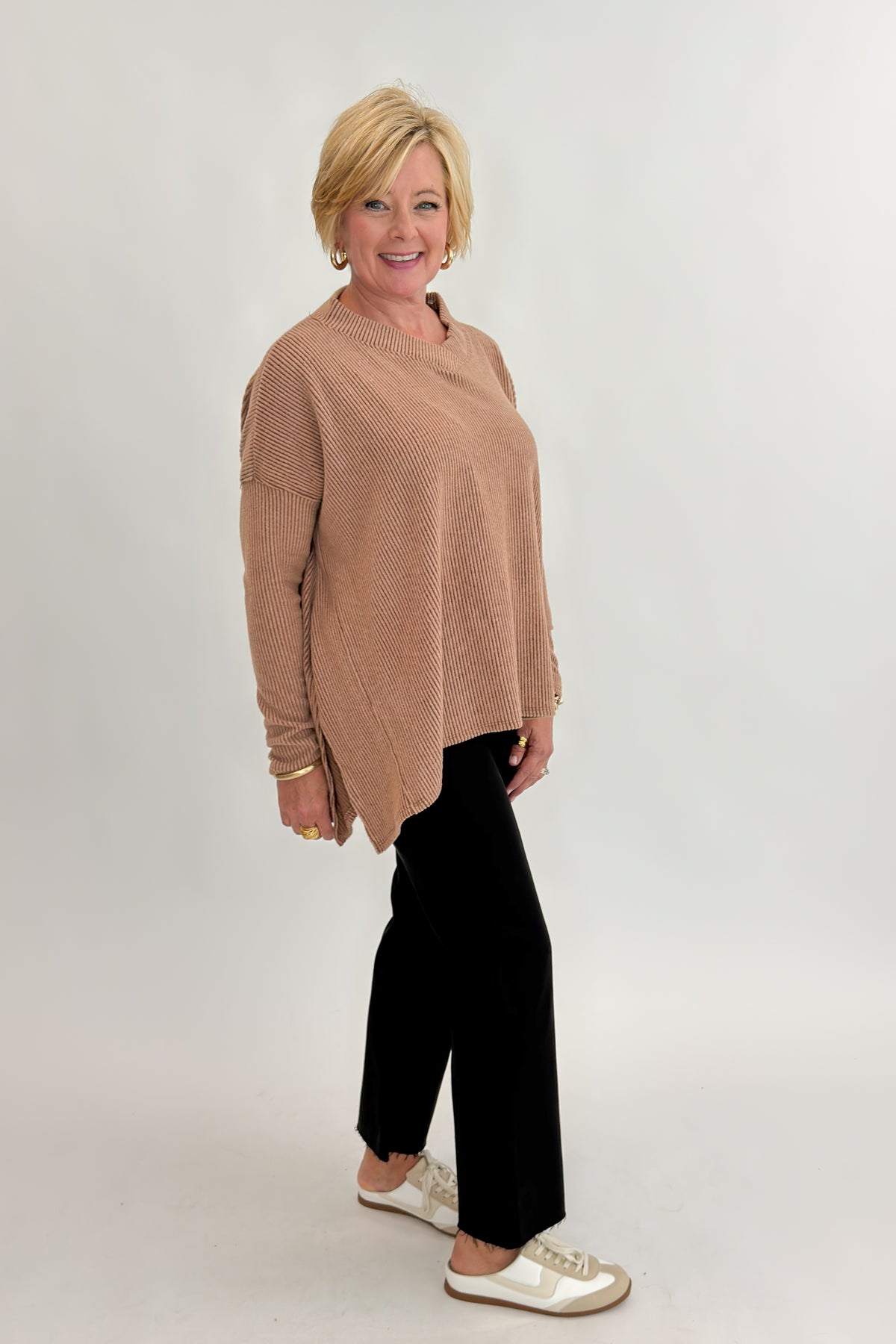 Side view of woman wearing Swagger Boutique’s Chestnut Brushed V-neck Top with jeans against white studio background.