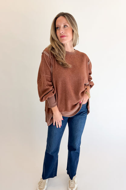Front view of woman wearing Swagger Boutique’s Chestnut Seam Detail Sweatshirt with jeans against white studio background.