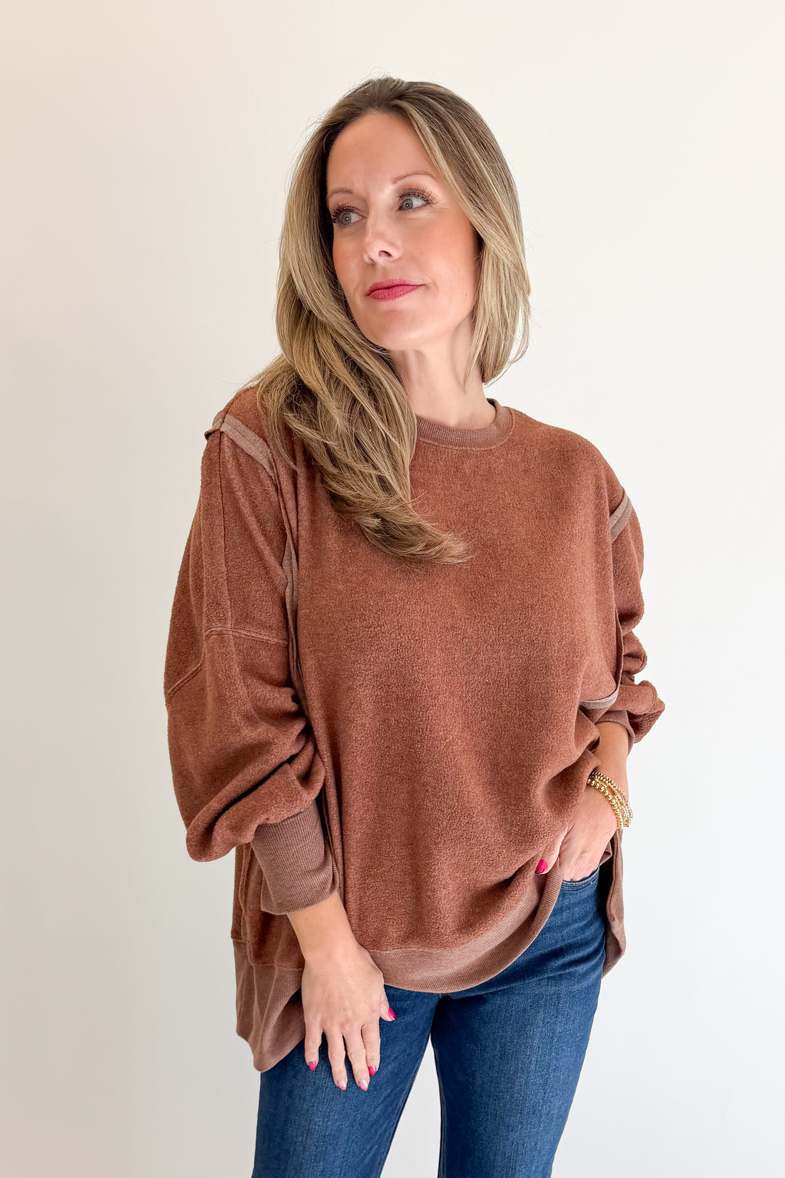 Front view of woman wearing Swagger Boutique’s Chestnut Seam Detail Sweatshirt with jeans against white studio background.