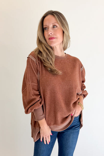 Front view of woman wearing Swagger Boutique’s Chestnut Seam Detail Sweatshirt with jeans against white studio background.