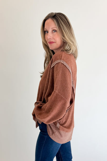 Side view of woman wearing Swagger Boutique’s Chestnut Seam Detail Sweatshirt with jeans against white studio background.