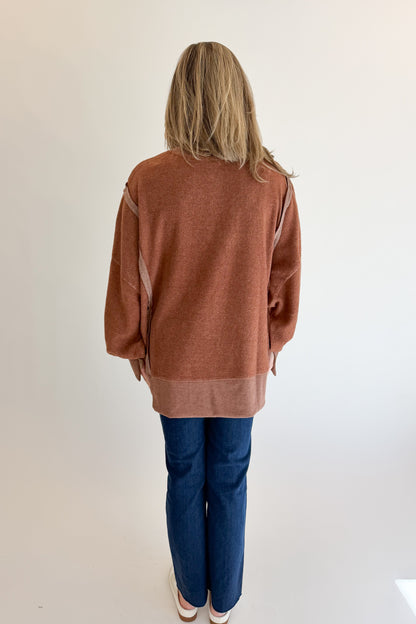 Back view of woman wearing Swagger Boutique’s Chestnut Seam Detail Sweatshirt with jeans against white studio background.