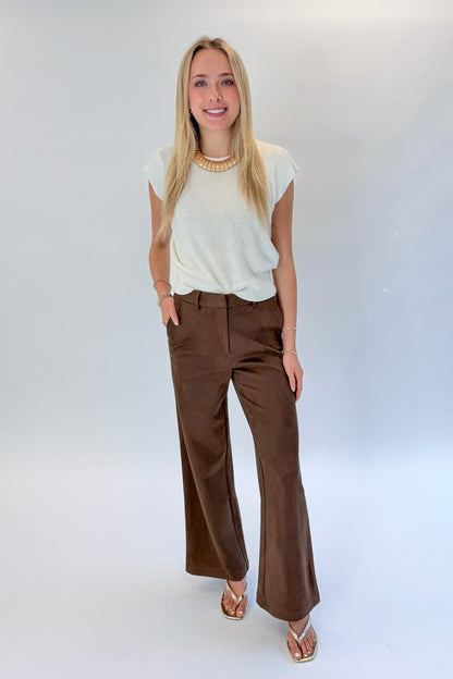 Front view of woman wearing Swagger Boutique’s Chocolate Brown Suede Pants with Living My Best Life White Cap Sleeve Sweater by PINCH against white studio background.