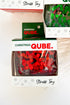 Two Christmas-themed stress toys by Christmas Qube. shown in their retail packaging on a white background.