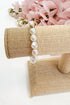 Pearl bracelet on a beige jewelry stand with pink flowers in the background