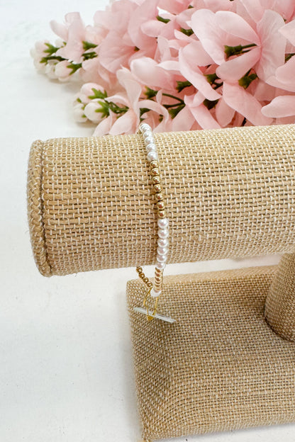 Pearl bracelet on a beige jewelry stand with pink flowers in the background