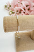 Pearl bracelet on a beige jewelry stand with pink flowers in the background