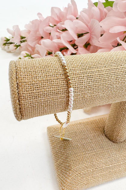 Pearl bracelet on a beige jewelry stand with pink flowers in the background