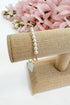 Pearl bracelet on a beige stand with pink flowers in the background