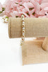 Pearl bracelet on a gold bracelet display with pink flowers in the background