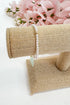 Pearl bracelet on a burlap stand with pink flowers in the background