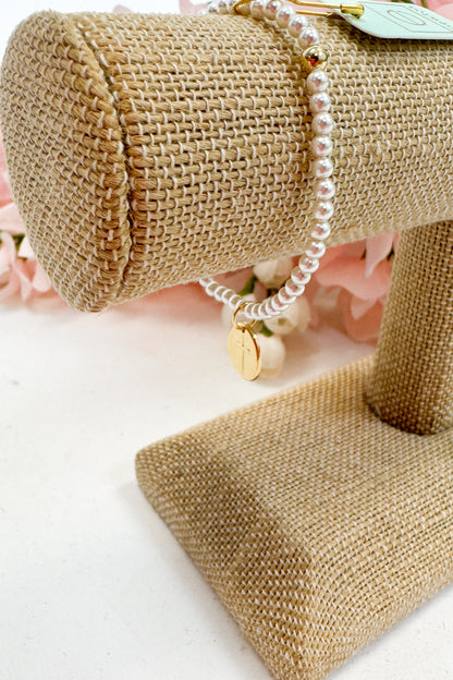 Pearl bracelet on a burlap roll with a pink floral background