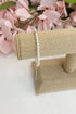 Pearl bracelet on a burlap stand with pink flowers in the background