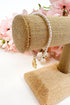 Pearl bracelet on a gold jewelry stand with pink flowers in the background