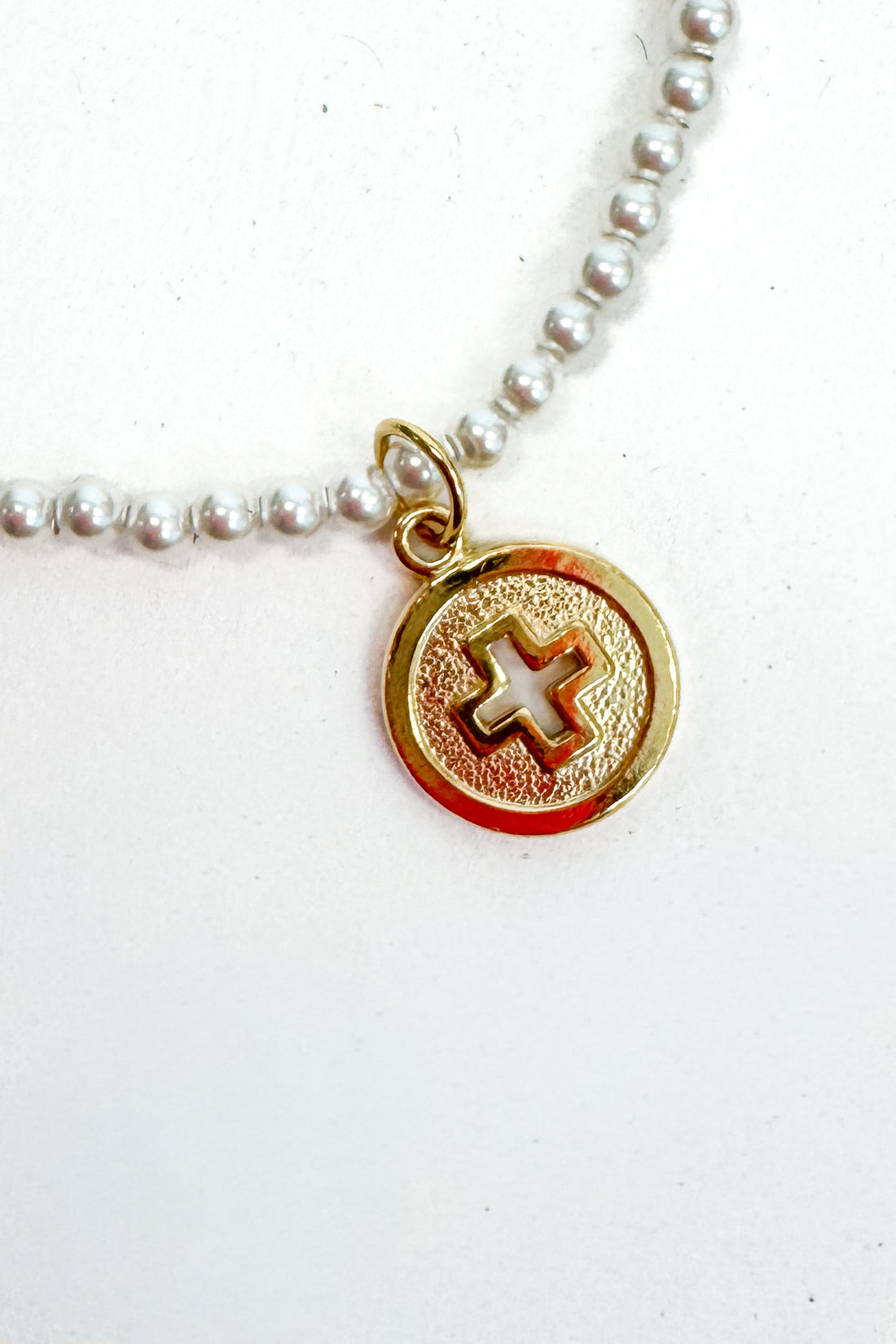 Necklace with a gold pendant featuring a cross on a white background