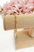Gold bracelet on a beige jewelry display with pink flowers in the background