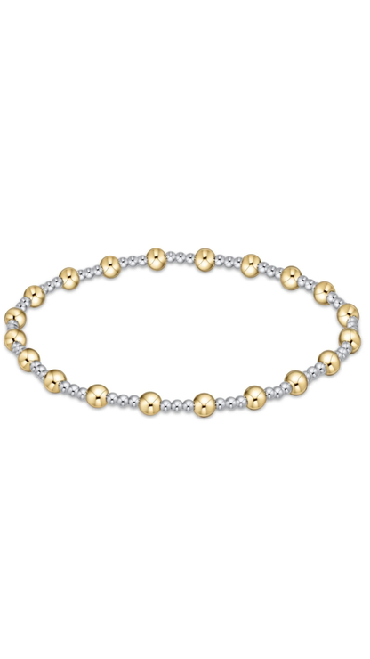 A delicate beaded bracelet featuring alternating polished yellow gold and textured silver beads, arranged in an oval shape against a solid white background.