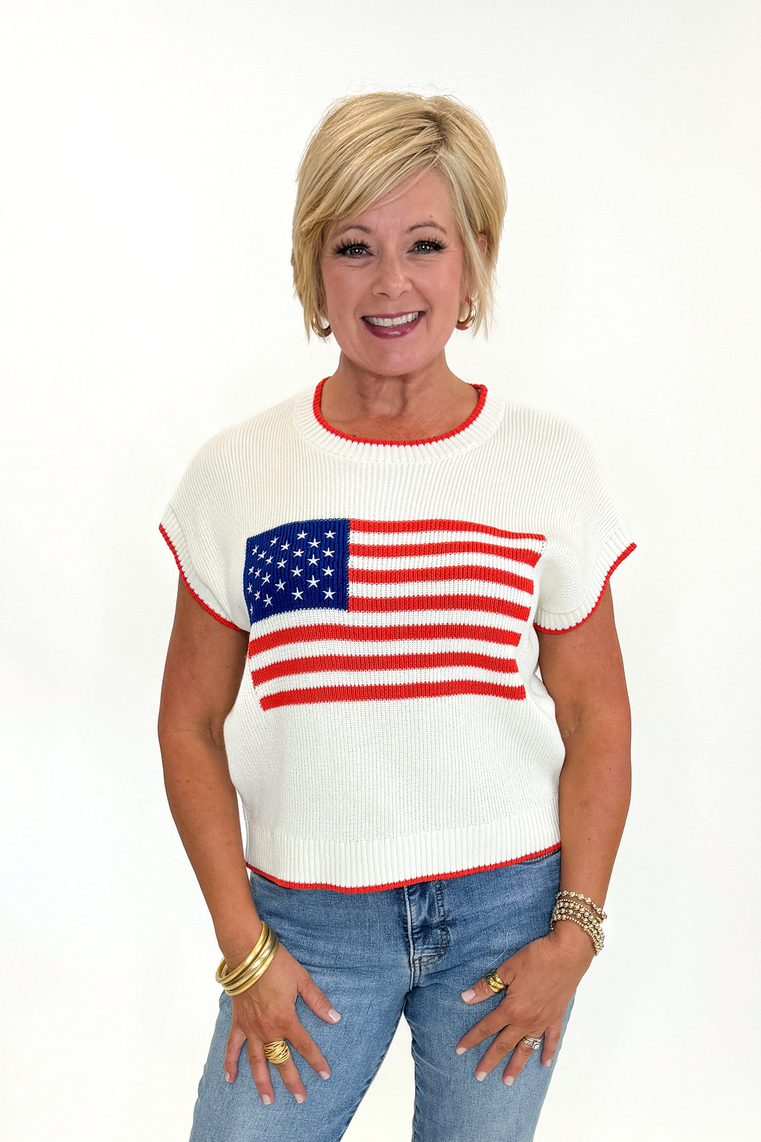 Front view of woman wearing Swagger Boutique’s  Sleeveless Patriot Sweater In Cloud by Z Supply with jeans and sandals against white studio background.
