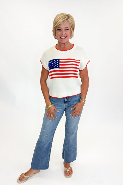 Front view of woman wearing Swagger Boutique’s  Sleeveless Patriot Sweater In Cloud by Z Supply with jeans and sandals against white studio background.