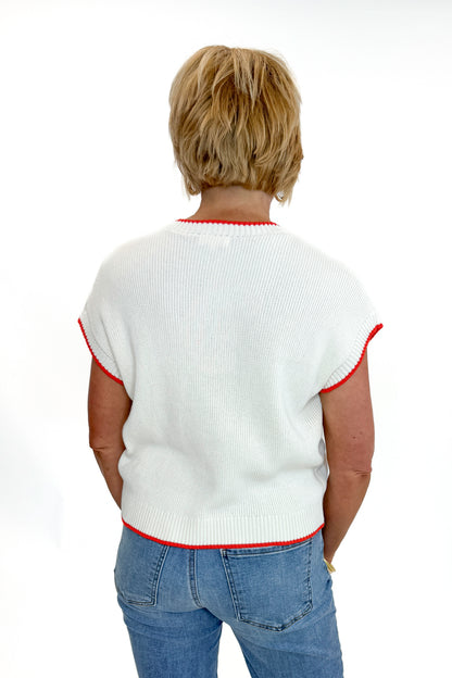 Back view of woman wearing Swagger Boutique’s  Sleeveless Patriot Sweater In Cloud by Z Supply with jeans and sandals against white studio background.