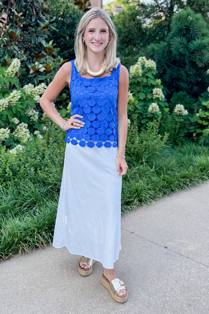 Front view of woman wearing Swagger Boutique’s Cobalt Sleeveless Lace Tank with white skirt standing outside by trees.