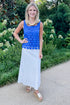 Front view of woman wearing Swagger Boutique’s Cobalt Sleeveless Lace Tank with white skirt standing outside by trees.