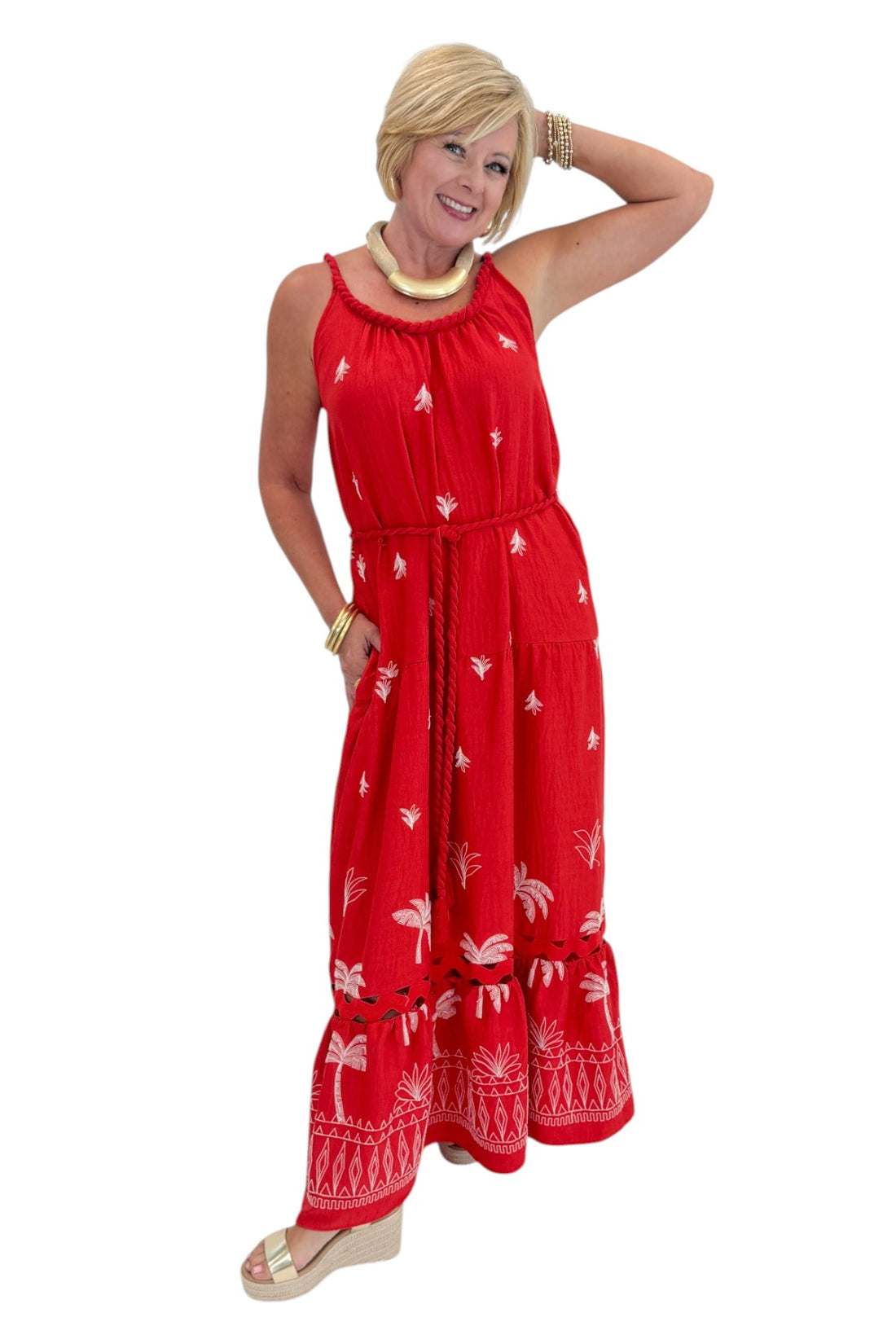 Front view of woman wearing Swagger Boutique’s Coral Palm Embroidered Maxi Dress with sandals against white studio background.