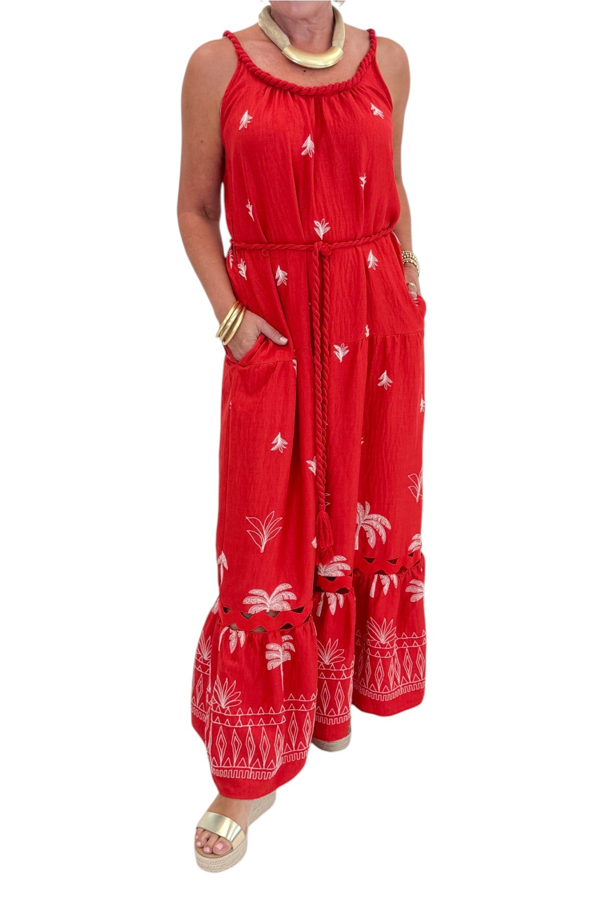 Front detail view of woman wearing Swagger Boutique’s Coral Palm Embroidered Maxi Dress with sandals against white studio background.