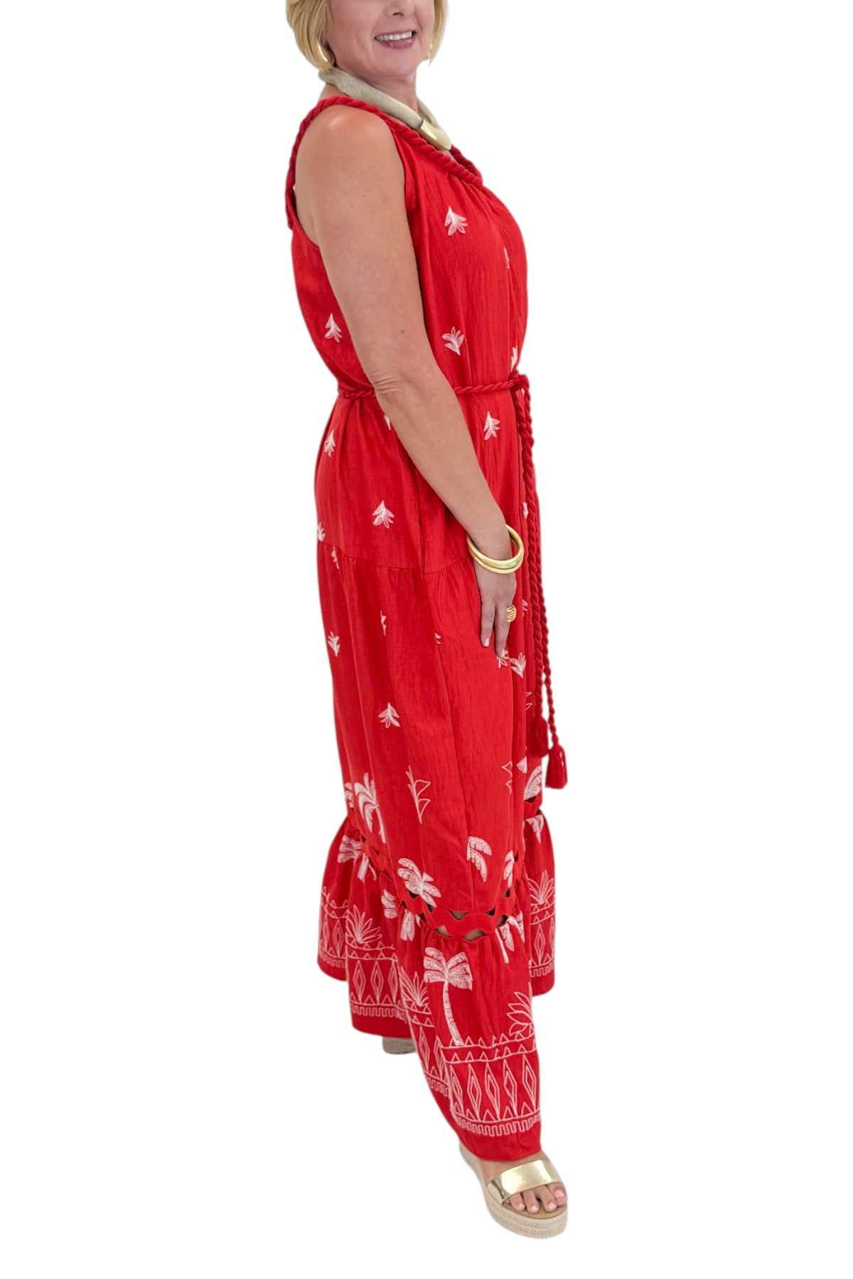 Side view of woman wearing Swagger Boutique’s Coral Palm Embroidered Maxi Dress with sandals against white studio background.