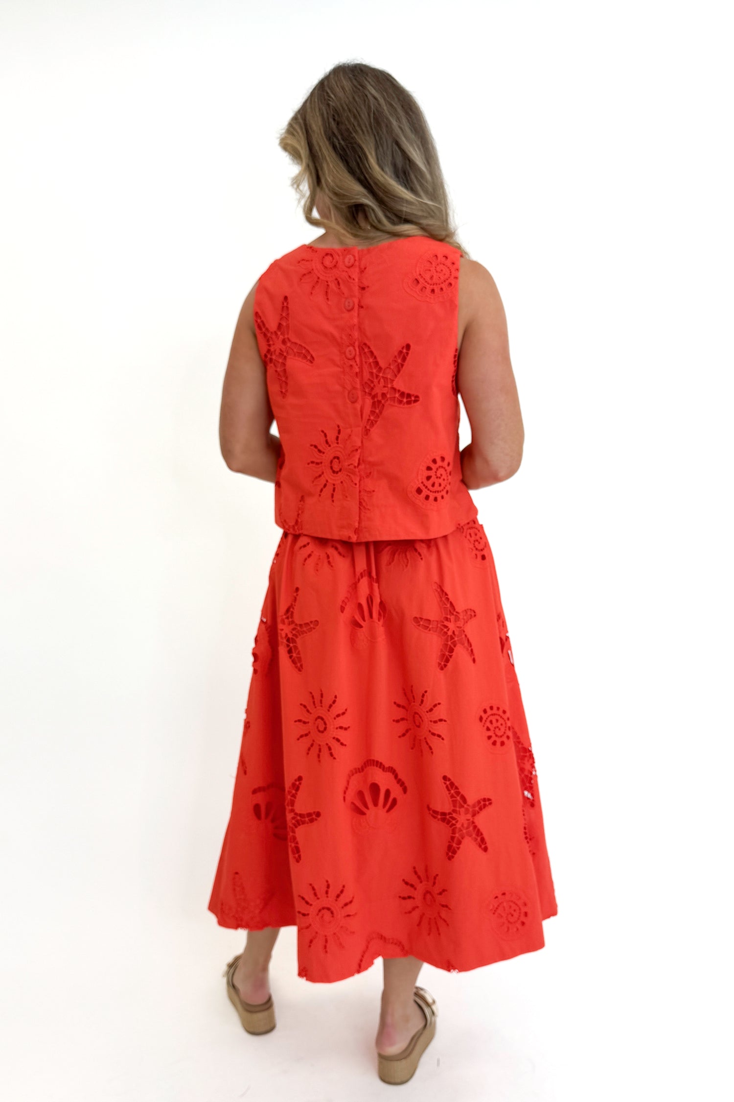 Back view of woman wearing Swagger Boutique’s Coral Shell Embroidered Tank with matching Coral Shell Embroidered Midi Skirt against white studio background.