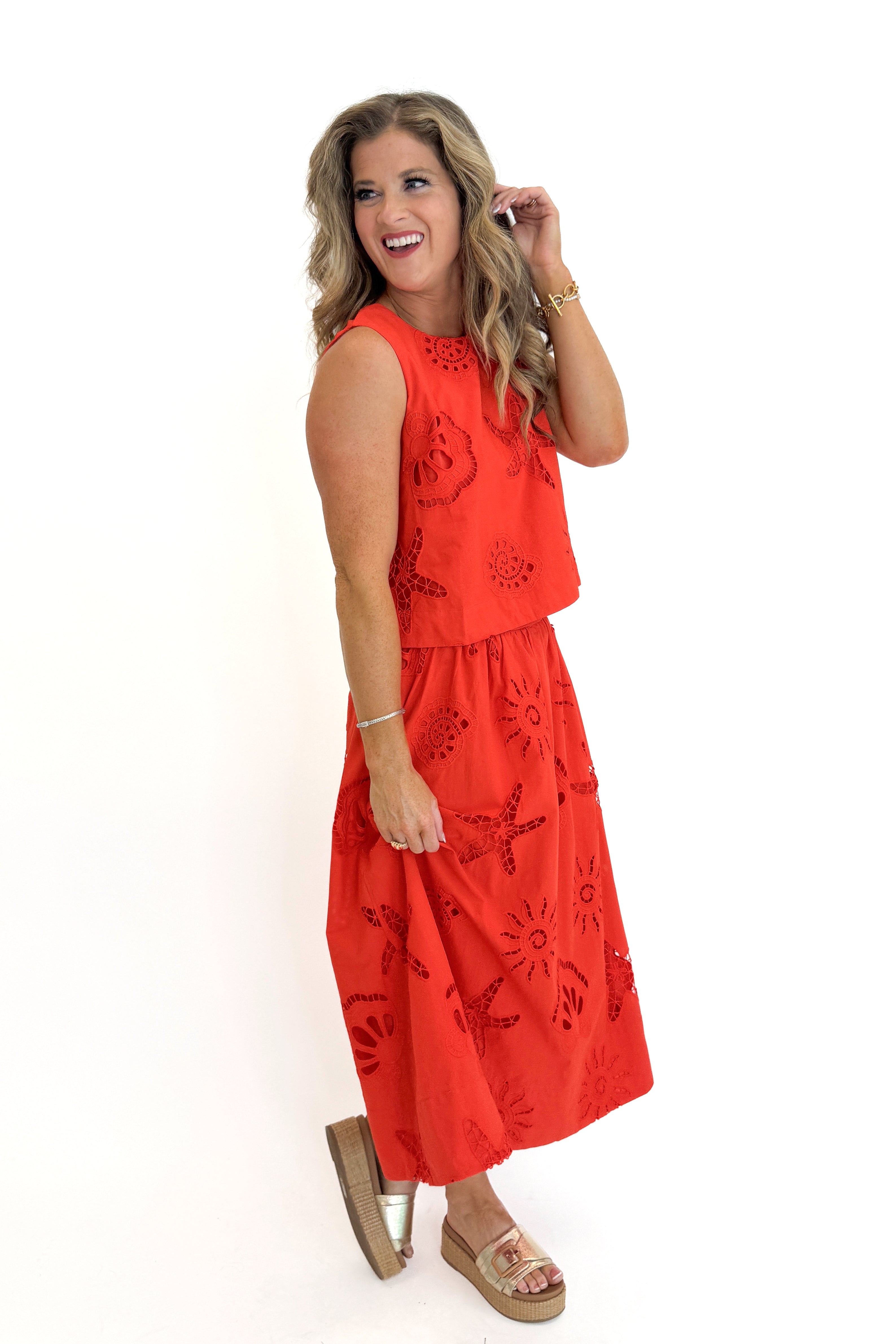 Side view of woman wearing Swagger Boutique’s Coral Shell Embroidered Tank with matching Coral Shell Embroidered Midi Skirt against white studio background.