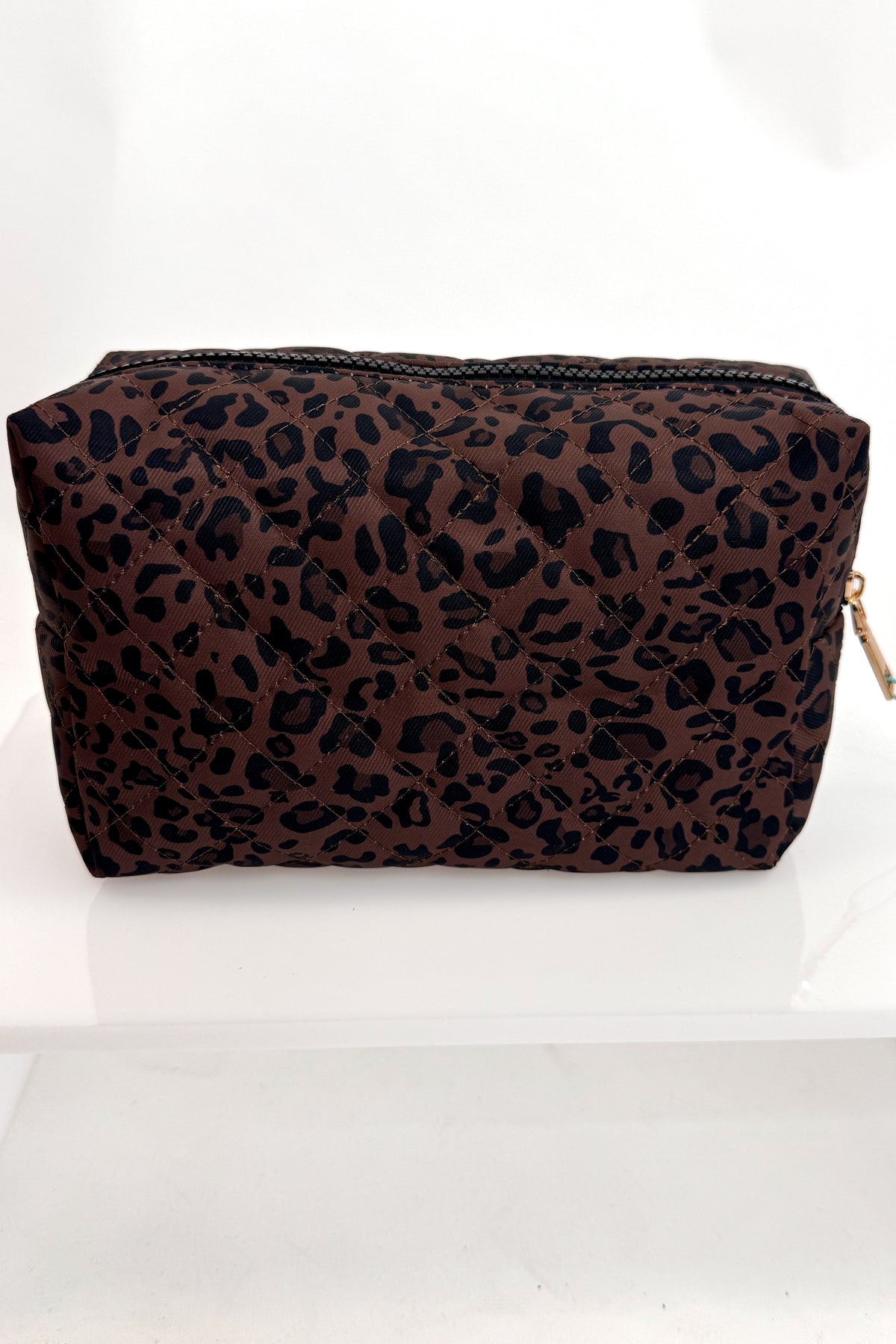 A rectangular cosmetic pouch with a brown and black leopard print pattern, featuring a black zipper closure and a small gold zipper pull, displayed on a white surface against a white background.