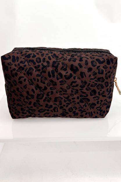 A rectangular cosmetic pouch with a brown and black leopard print pattern, featuring a black zipper closure and a small gold zipper pull, displayed on a white surface against a white background.
