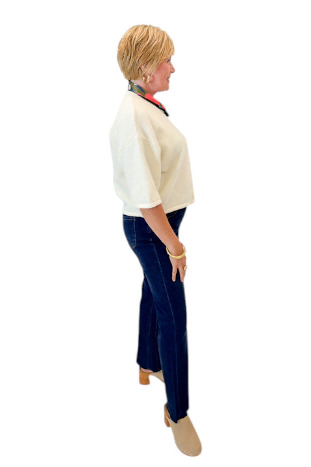 Side view of woman wearing Swagger Boutique’s Cream Button Down Short Sleeve Sweater by PINCH with jeans against white studio background.