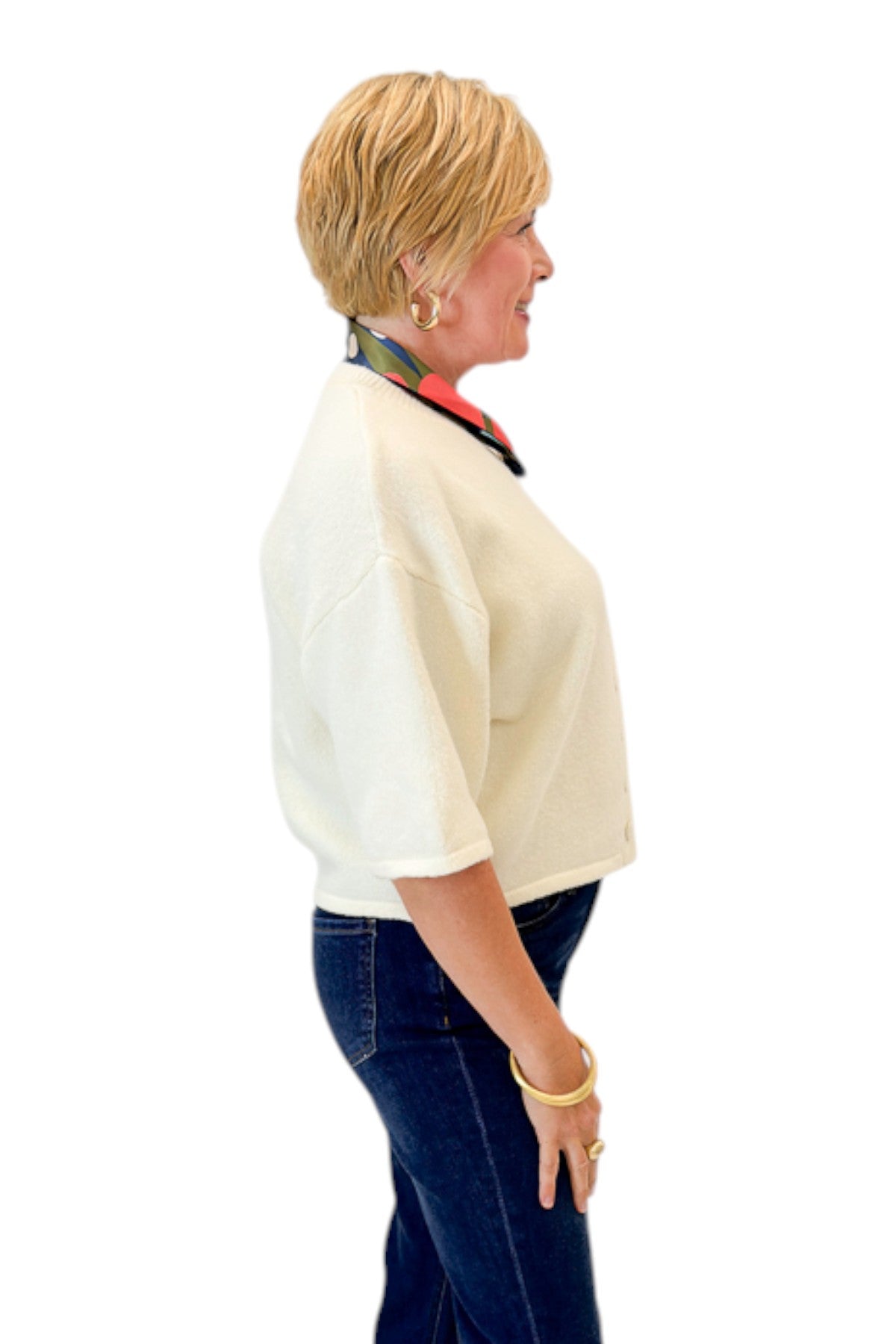 Side view of woman wearing Swagger Boutique’s Cream Button Down Short Sleeve Sweater by PINCH with jeans against white studio background.