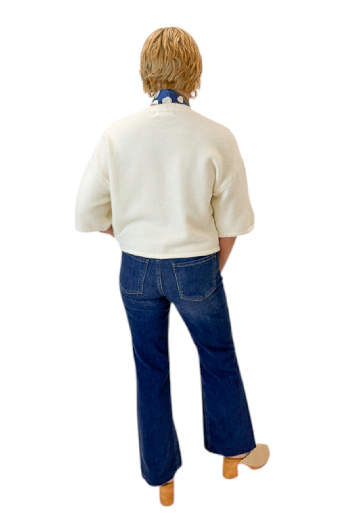 Back view of woman wearing Swagger Boutique’s Cream Button Down Short Sleeve Sweater by PINCH with jeans against white studio background.