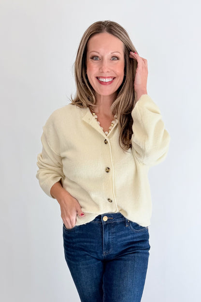 Front view of woman wearing Swagger Boutique’s Cream Button Up Cardigan with jeans against white studio background.