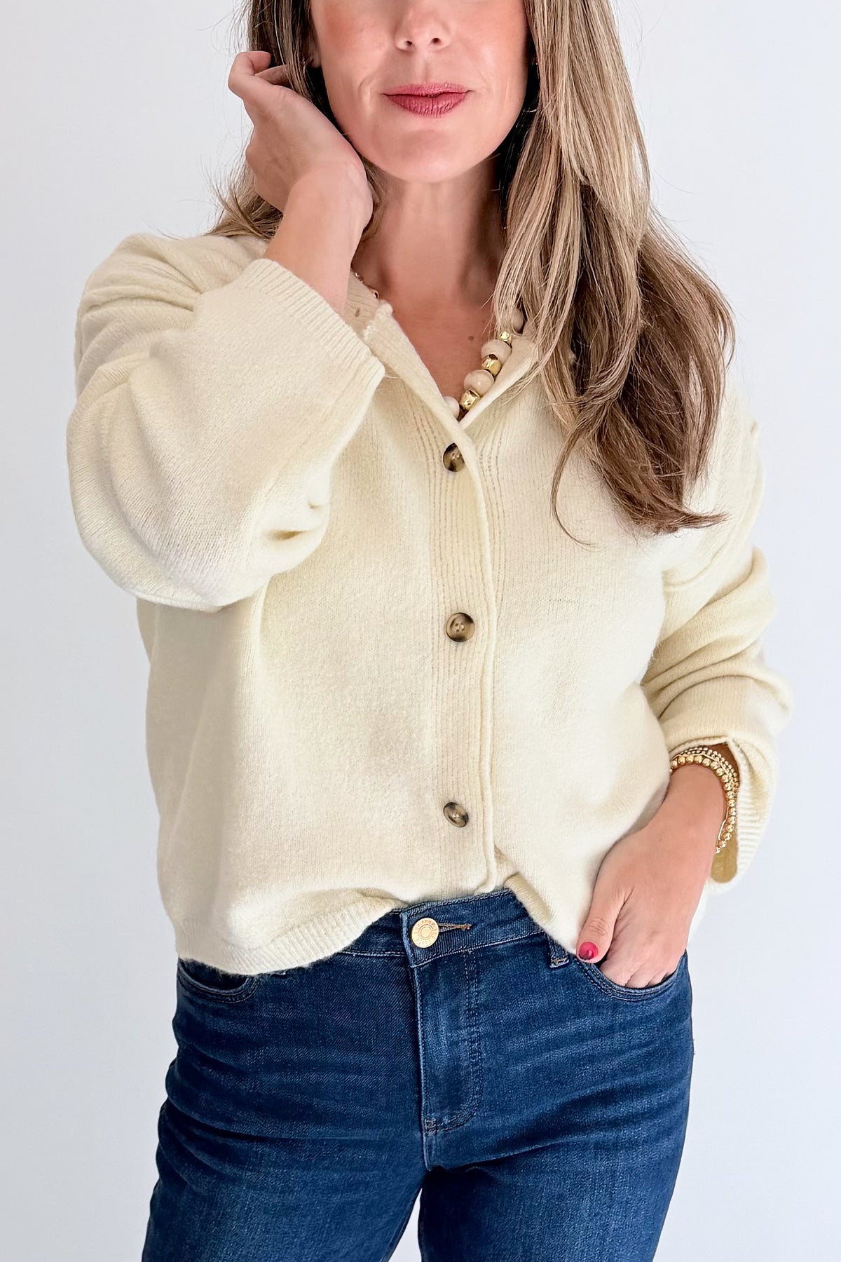 Front detail view of woman wearing Swagger Boutique’s Cream Button Up Cardigan with jeans against white studio background.