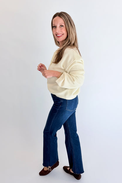 Side view of woman wearing Swagger Boutique’s Cream Button Up Cardigan with jeans against white studio background.