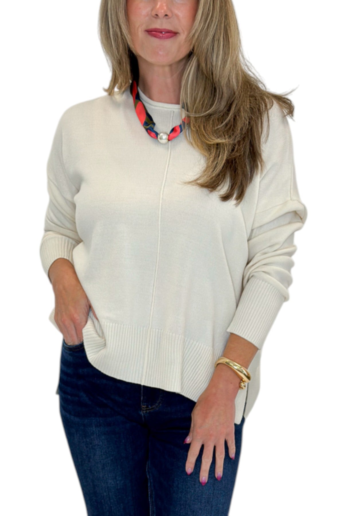 Front detail view of woman wearing Swagger Boutique’s Cream Center Seam Round Neck Sweater with jeans against white studio background.