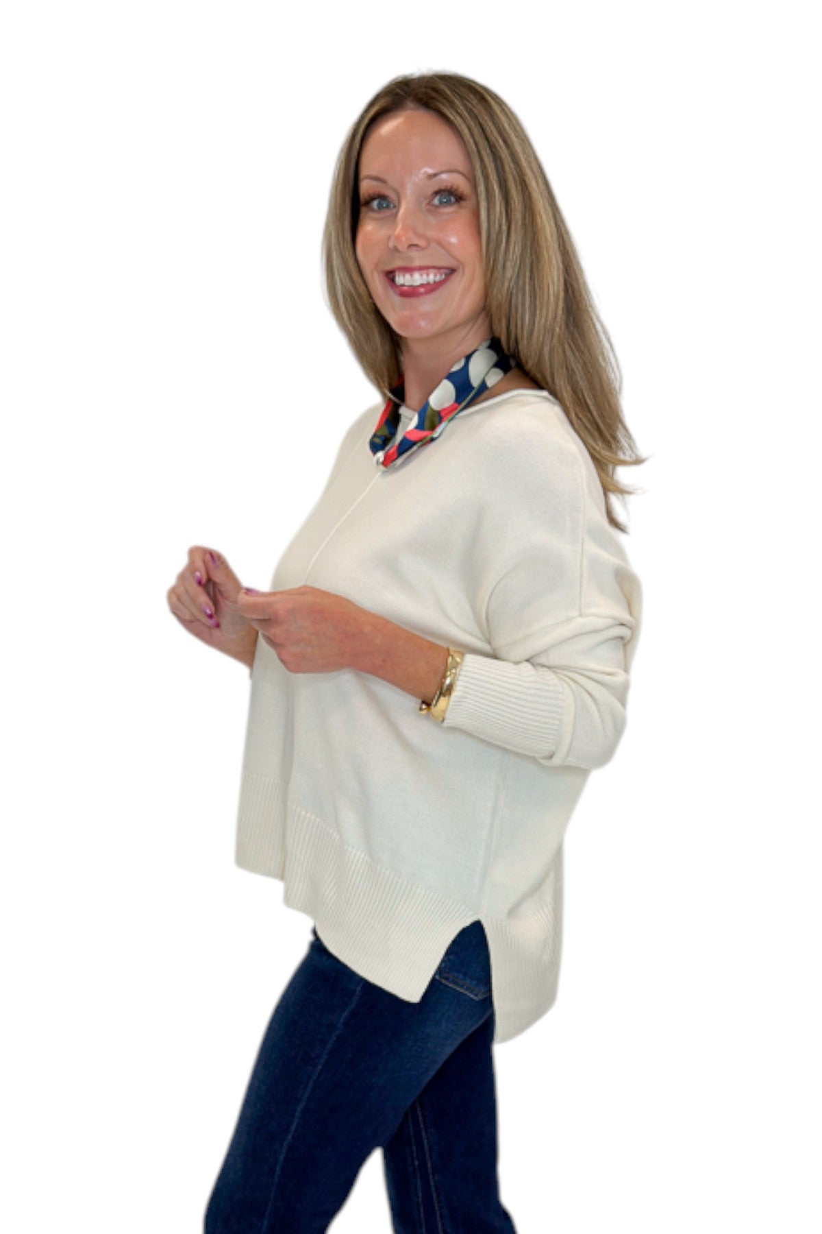 Side view of woman wearing Swagger Boutique’s Cream Center Seam Round Neck Sweater with jeans against white studio background.