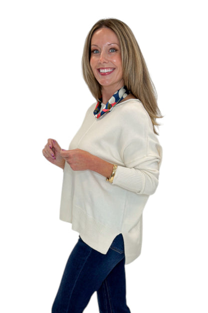 Side view of woman wearing Swagger Boutique’s Cream Center Seam Round Neck Sweater with jeans against white studio background.