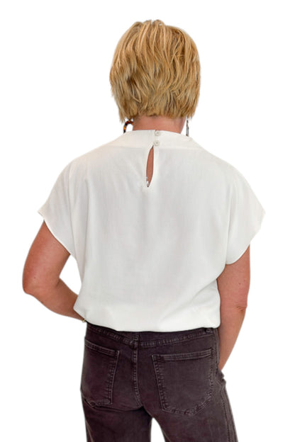Back view of woman wearing Swagger Boutique’s Cream Cowl Neck Top with jeans against white studio background.