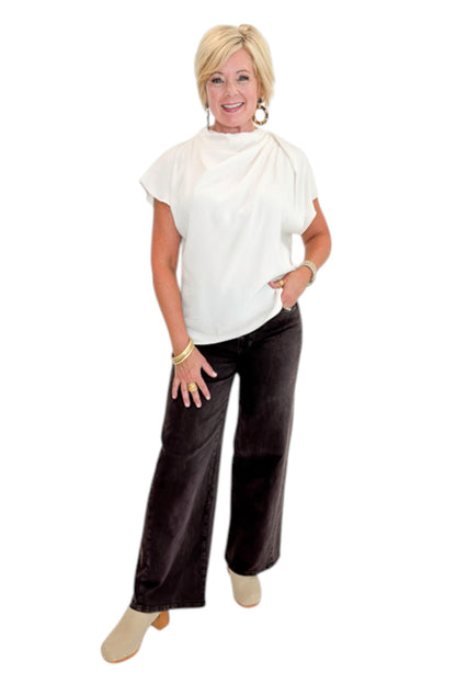 Front view of woman wearing Swagger Boutique’s Cream Cowl Neck Top with jeans against white studio background.