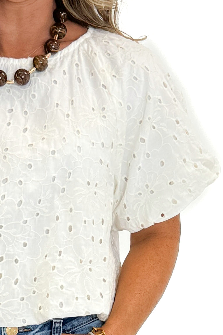 Front detail view of woman wearing Swagger Boutique’s Cream Eyelet Bubble Hem Top with jeans against white studio background.