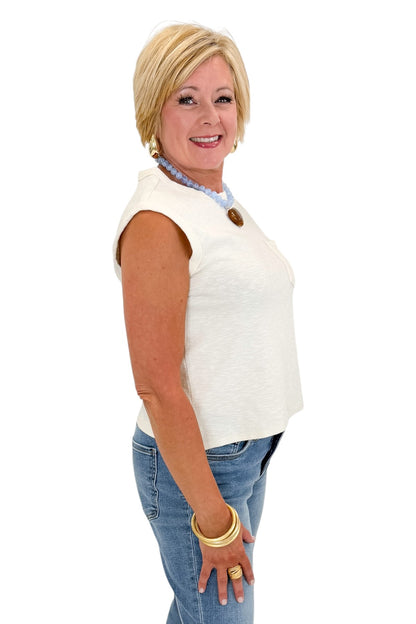 Side view of woman wearing Swagger Boutique’s Cream Pocket Detail Tank with jeans against white studio background.