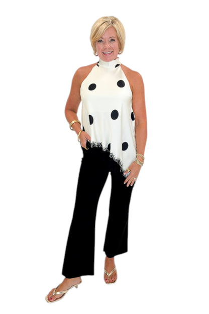 Front view of woman wearing Swagger Boutique’s Cream Polka Dot Asymmetrical Halter Neck Satin Lace Top by Entro with jeans against white studio background.